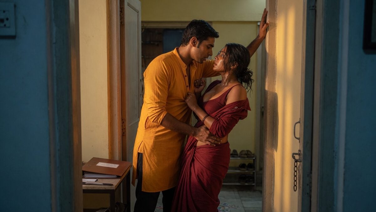 Two fully clothed adults, one adult Indian man and one adult Indian woman in an Indian apartment entry.