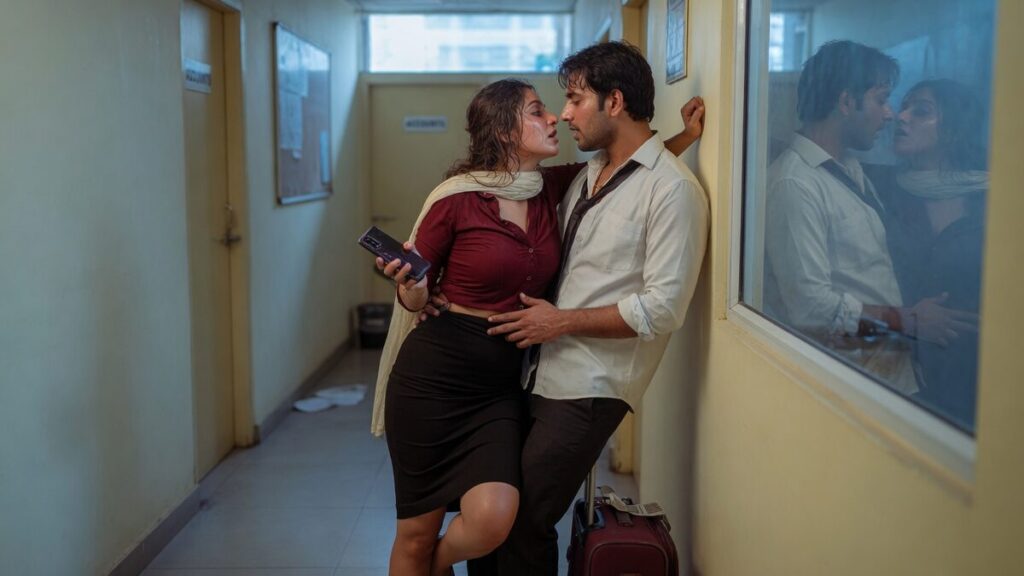 Two fully clothed fictional adult Indian household visitors, both clearly age 21 or older in an after-hours Indian office corridor, in natural daytime light, with a mobile phone and a small suitcase.