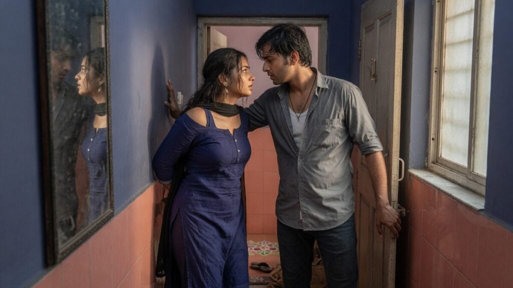 Two fully clothed adults, one adult Indian man and one adult Indian woman in an Indian apartment entry.