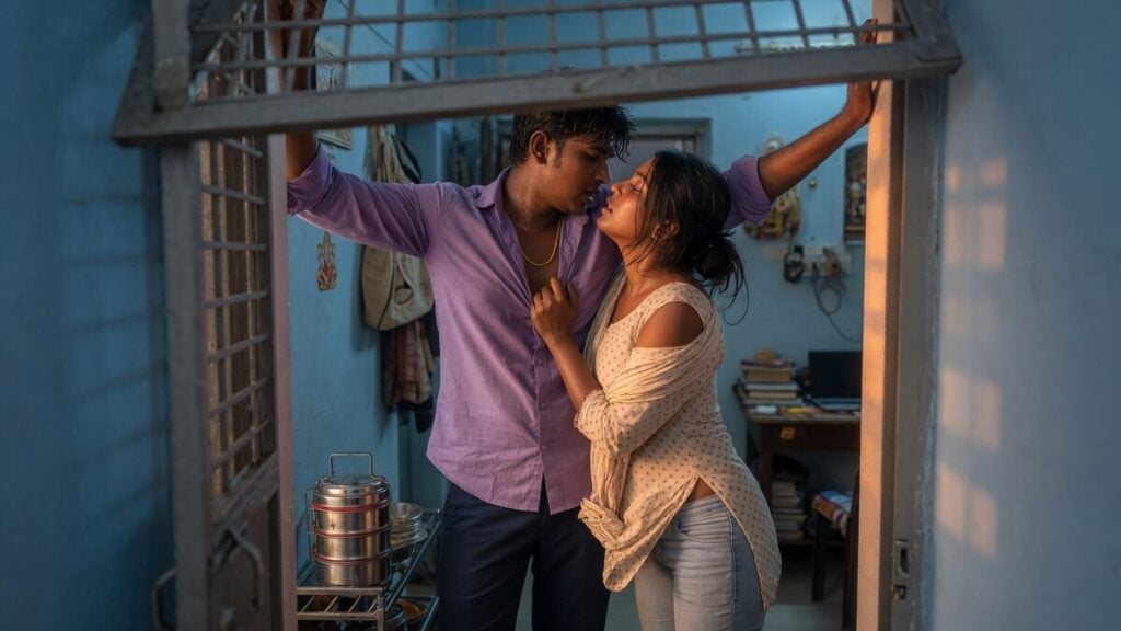 Two fully clothed adults, one adult Indian woman and one adult Indian woman in an Indian apartment entry.