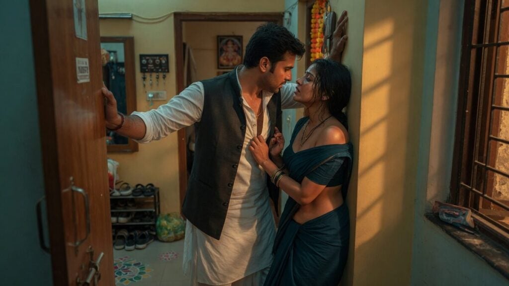 Two fully clothed adults, one adult Indian man and one adult Indian woman in an Indian apartment entry.
