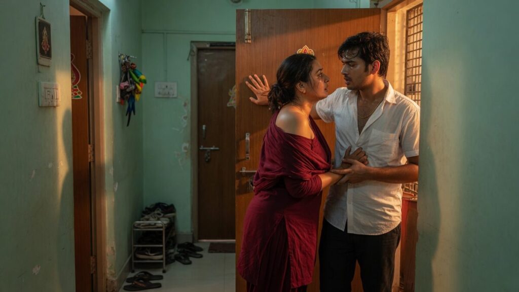 Two fully clothed adults, one adult Indian man and one adult Indian woman in an Indian apartment entry.