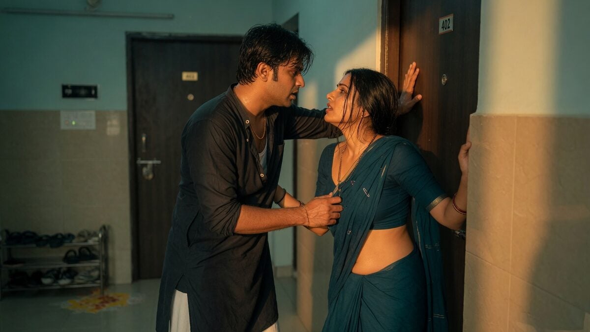 Two fully clothed adults, one adult Indian man and one adult Indian woman in a contemporary Indian city apartment entry.