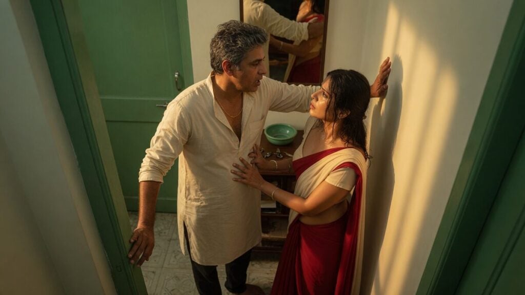 Two fully clothed adults, one adult Indian man and one adult Indian woman in an Indian apartment entry.