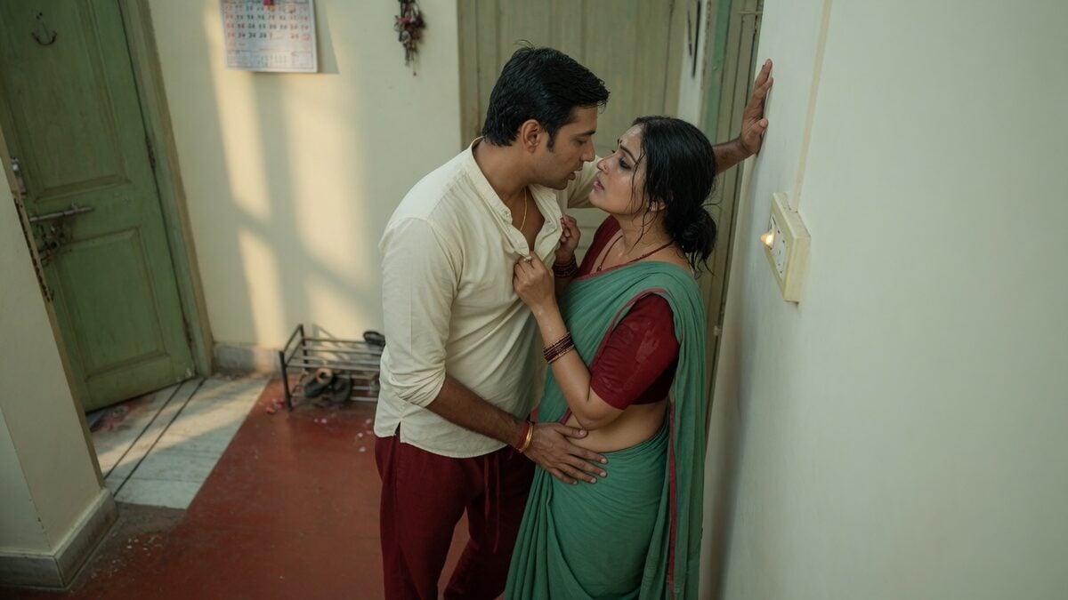 Two fully clothed adults, one adult Indian man and one adult Indian woman in an Indian apartment entry.