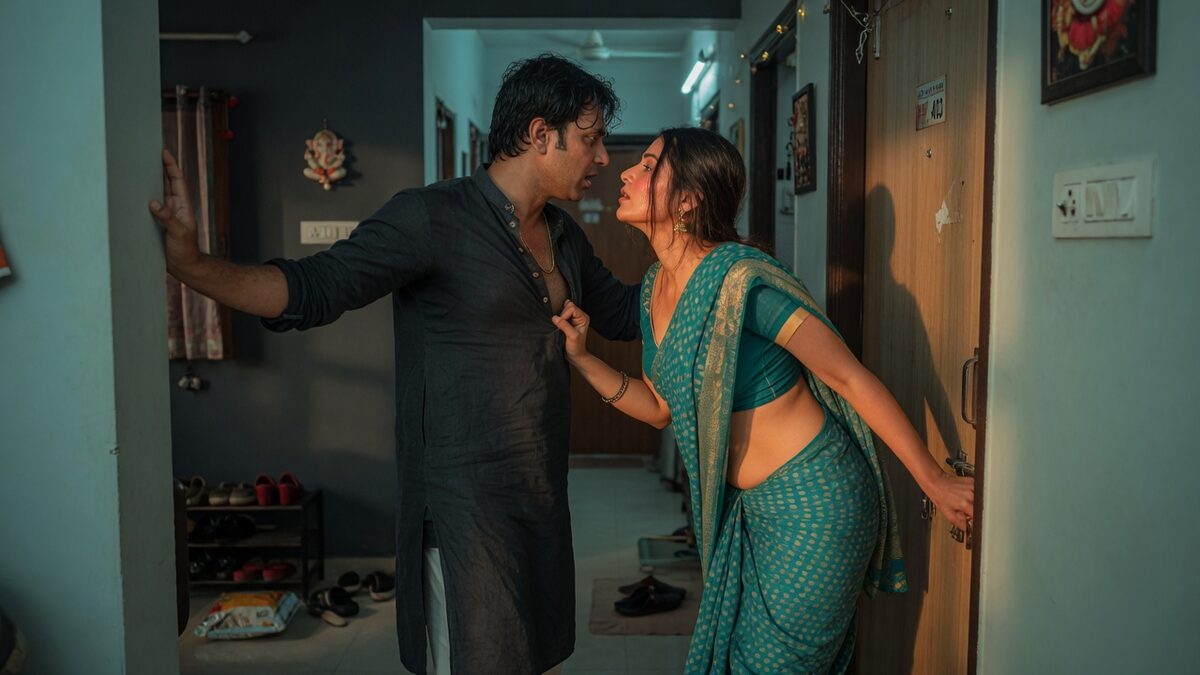 Two fully clothed adults, one adult Indian man and one adult Indian woman in a contemporary Indian city apartment entry.