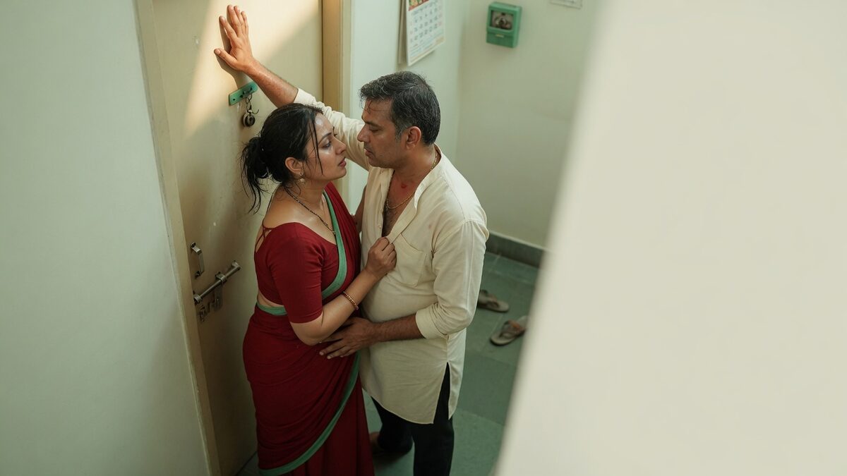 Two fully clothed adults, one adult Indian woman and one adult Indian man in an Indian apartment entry.