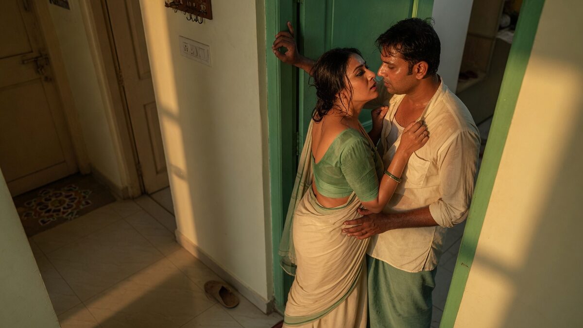 Two fully clothed adults, one adult Indian woman and one adult Indian man in an Indian apartment entry.